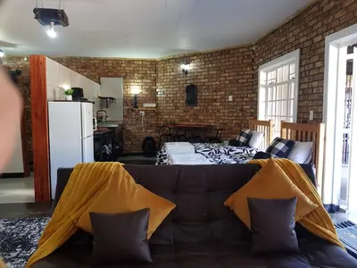 a living room with a couch and a brick wall at 2K City Studios Not Self catering in Graskop