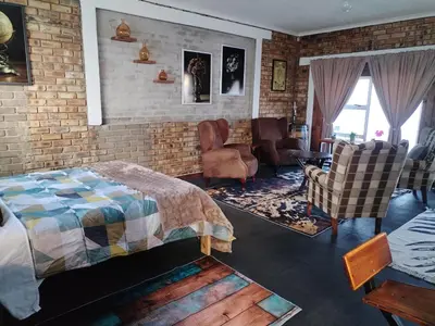 a bedroom with a bed and a brick wall at 2K City Studios Not Self catering in Graskop