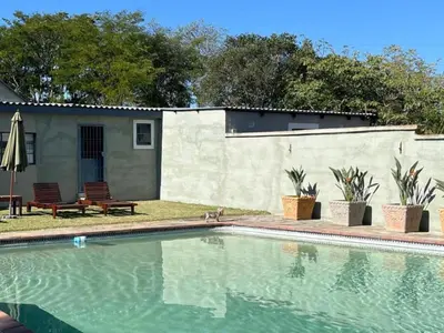 a swimming pool in front of a house with a building at BelofteBos Farmhouse Inn in Bandelierkop