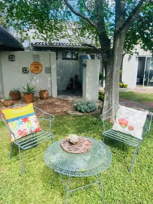 two chairs and a glass table in a yard at BelofteBos Farmhouse Inn in Bandelierkop