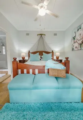 a bedroom with a bed with a blue ottoman at BelofteBos Farmhouse Inn in Bandelierkop