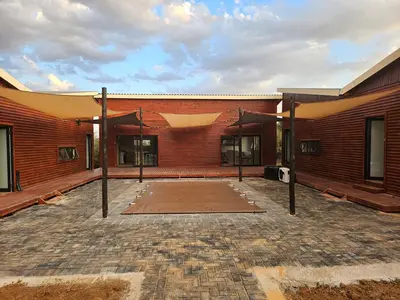 a large brick building with a patio in front of it at Emintha Log House in Mmukubyane