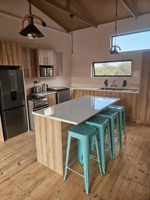 a kitchen with a large island with blue stools at Emintha Log House in Mmukubyane