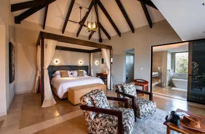 a bedroom with a large bed and a bathroom at Idube Game Reserve in Sabi Sand Game Reserve
