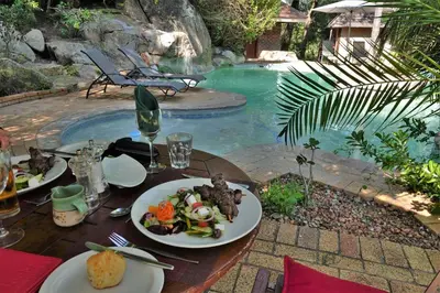 a table with plates of food next to a swimming pool at Idube Game Reserve in Sabi Sand Game Reserve