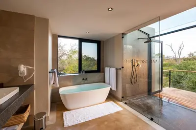 a bathroom with a tub and a glass shower at Idube Game Reserve in Sabi Sand Game Reserve
