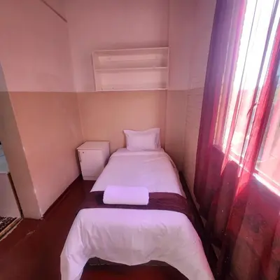a small bed in a small room with a window at Sunny Lodge in Pretoria