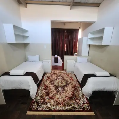 a room with three beds with a rug in it at Sunny Lodge in Pretoria