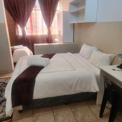 a bedroom with a large white bed with a window at Sunny Lodge in Pretoria
