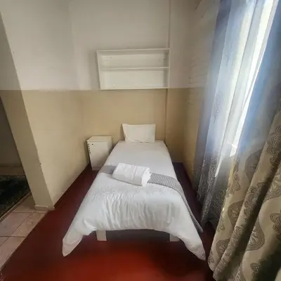 a small bed in a small room with a window at Sunny Lodge in Pretoria