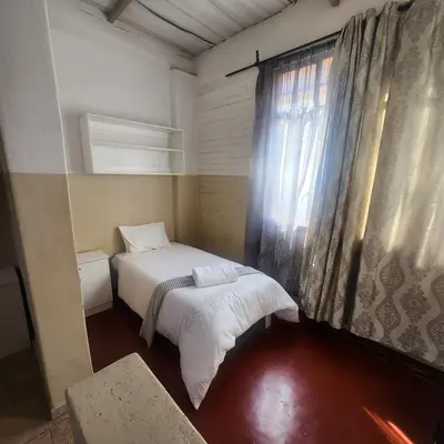 a small bedroom with a bed and a window at Sunny Lodge in Pretoria