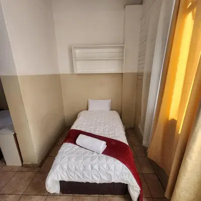 a small room with a bed with two towels at Sunny Lodge in Pretoria