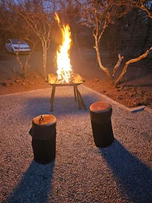 a fire pit with two logs and two stools at Thirty-Three Dinokeng Big 5 with a hot tub in Klipdrift