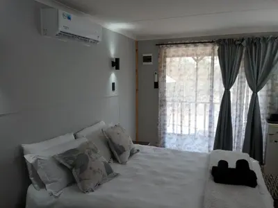 a bedroom with a white bed with a window at Thirty-Three Dinokeng Big 5 with a hot tub in Klipdrift