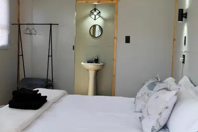 a bedroom with a white bed and a sink at Thirty-Three Dinokeng Big 5 with a hot tub in Klipdrift