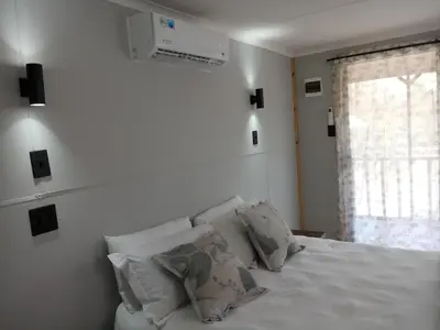 a bedroom with a white bed with pillows and a window at Thirty-Three Dinokeng Big 5 with a hot tub in Klipdrift