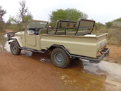 a tan jeep parked on a dirt road at Thirty-Three Dinokeng Big 5 with a hot tub in Klipdrift