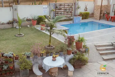 a garden with a table and potted plants and a pool at Sunpalm Guesthouse in Nelspruit