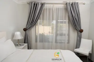 a bedroom with a bed and a window with curtains at Sunpalm Guesthouse in Nelspruit