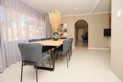 a dining room with a wooden table and chairs at Sunny villa with pool and garden in Pretoria
