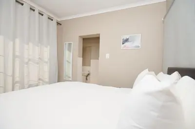 a white bedroom with a bed with white pillows at Sunny villa with pool and garden in Pretoria