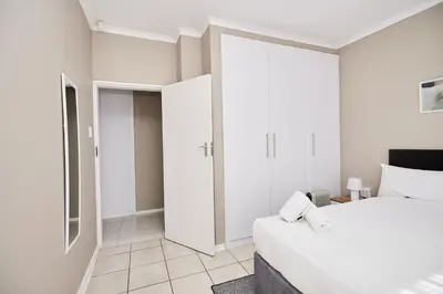 a white bedroom with a bed and a walk in closet at Sunny villa with pool and garden in Pretoria