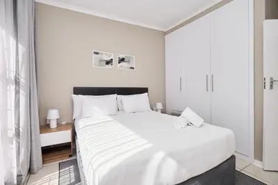 a white bedroom with a large bed and a window at Sunny villa with pool and garden in Pretoria