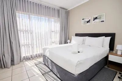 a bedroom with a large white bed and a large window at Sunny villa with pool and garden in Pretoria