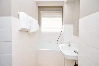 a white bathroom with a sink and a bath tub at Sunny villa with pool and garden in Pretoria