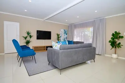 a living room with a gray couch and blue chairs at Sunny villa with pool and garden in Pretoria