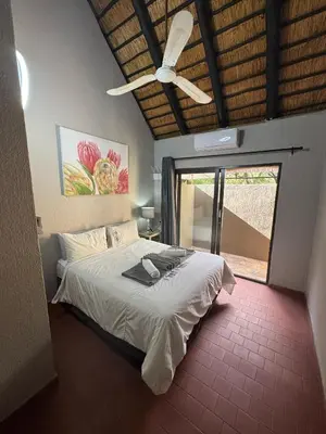 a bedroom with a bed and a ceiling fan at Singwe Private Safari Lodge Kruger in Marloth Park