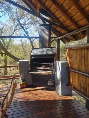 a outdoor grill on a deck with a wooden porch at Singwe Private Safari Lodge Kruger in Marloth Park