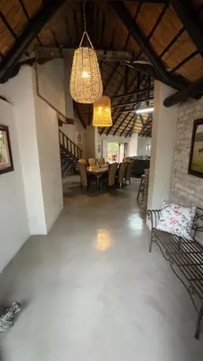 a living room with a chandelier and a table and chairs at Singwe Private Safari Lodge Kruger in Marloth Park