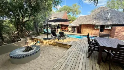 a house with a wooden deck with a table and an umbrella at Singwe Private Safari Lodge Kruger in Marloth Park