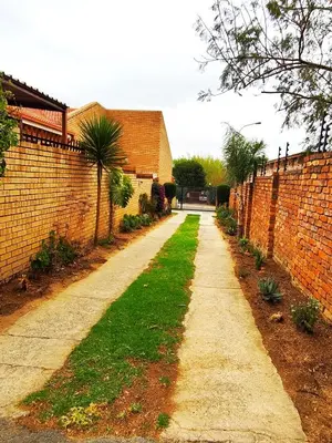 a brick alley way with a brick wall and grass at Ikhayalethu in Centurion