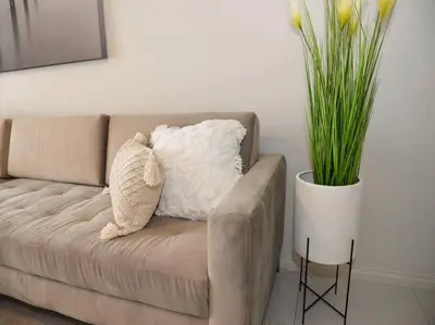 a couch with a pillow on it next to a plant at Elcaro Luxury Villas - Urban Taupe 1 in Midrand