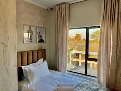 a bedroom with a bed and a large window at Cozy Retreat in Carlswald 229 in Midrand