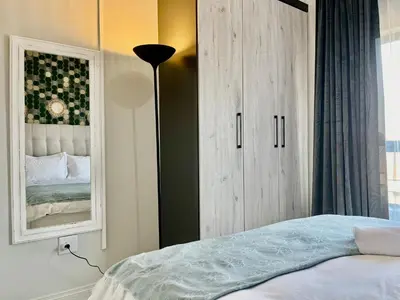a bedroom with a bed and a cabinet with a mirror at Cozy Retreat in Carlswald 229 in Midrand
