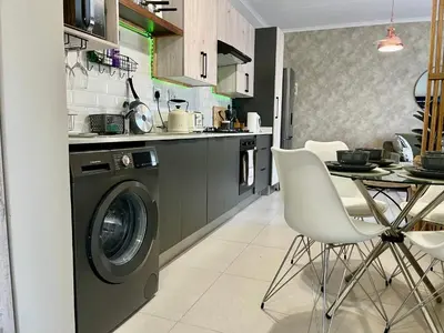 a kitchen with a washing machine and a table at Cozy Retreat in Carlswald 229 in Midrand