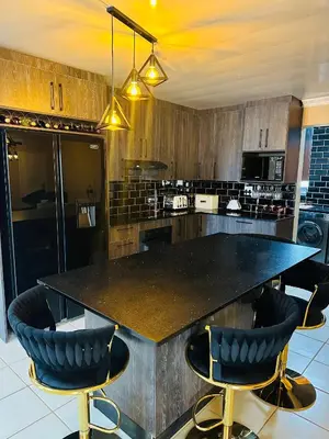 a kitchen with a large black counter and chairs at Jobak Farm House in Bela-Bela