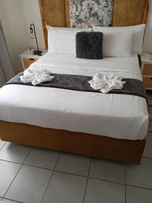 a bedroom with a bed with two white flowers on it at Menlyn Place City Vibes in Pretoria