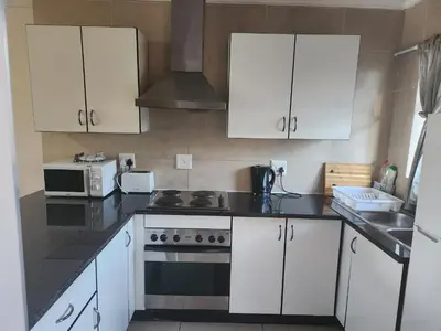 a kitchen with white cabinets and a stove and a microwave at Menlyn Place City Vibes in Pretoria