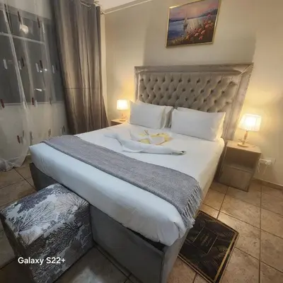 a bedroom with a large bed with a large white bedspread at Menlyn Place City Vibes in Pretoria
