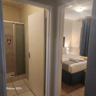 a bedroom with a bed and a walk in shower at Menlyn Place City Vibes in Pretoria