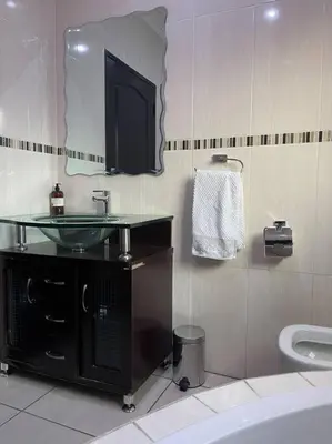 a bathroom with a sink and a mirror and a toilet at TG Villa Menlyn in Pretoria