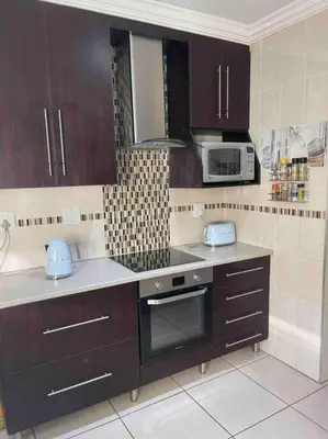 a kitchen with dark wood cabinets and a microwave at TG Villa Menlyn in Pretoria