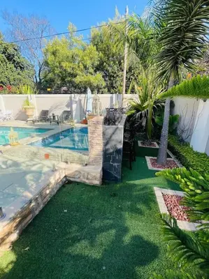 a backyard with a swimming pool and a palm tree at TG Villa Menlyn in Pretoria