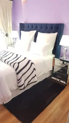 a bed with a black and white comforter and two lamps at Dali in Pretoria