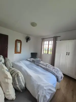 a white bedroom with a large bed and a window at Cozy Cabin in Dullstroom