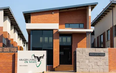a brick building with a sign in front of it at Kruger Living on Nyati in Malelane